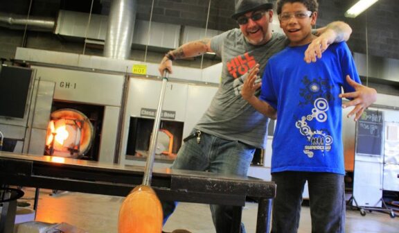 Hilltop Artists instructor Greg Piercy poses with a student in the hot shop