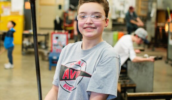 Hilltop Artist Aceline shows off a blown glass heart crafted in the hot shop