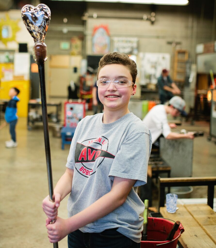 Hilltop Artist Aceline shows off a blown glass heart crafted in the hot shop