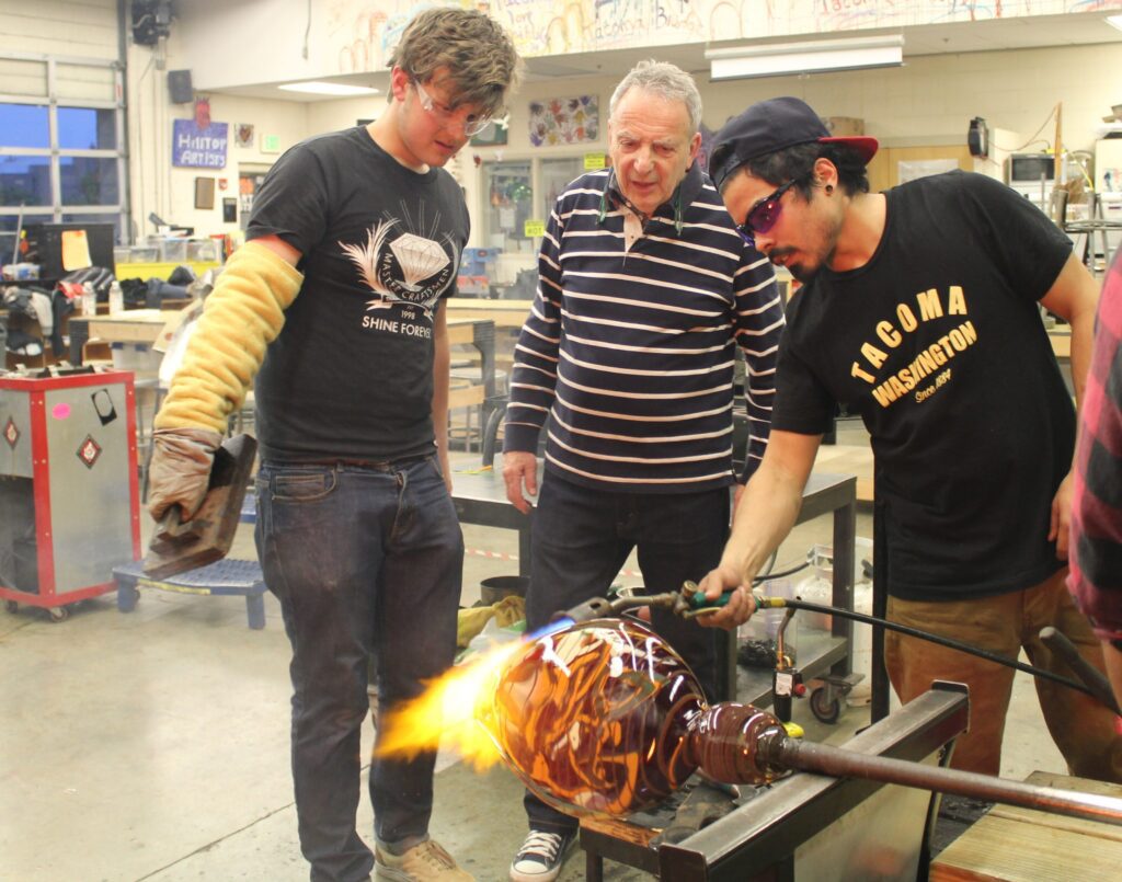 Hilltop Artist student Peter assists in the hot shop during a demonstration.