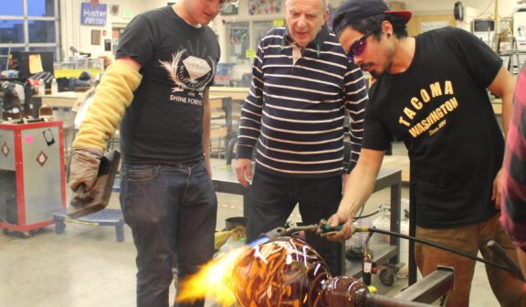 Hilltop Artist student Peter assists in the hot shop during a demonstration.
