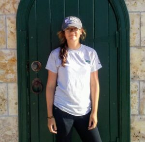 Hilltop Artist student Samantha poses for a photo in front of a green door.