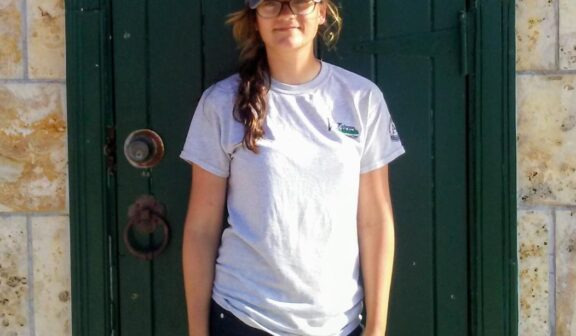 Hilltop Artist student Samantha poses for a photo in front of a green door.