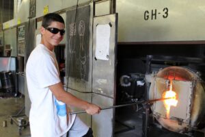Hilltop Artist Ari heats a glass piece in the furnace at Hilltop Heritage MS