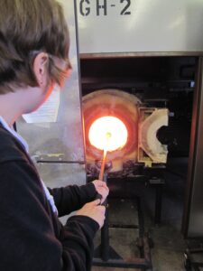 Hilltop Artist at the furnace while working on a glass piece in the hot shop.