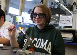 Hilltop Artist Emily works on a bead on the torch in the hot shop.