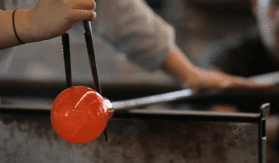 Hilltop Artist student works on a blown glass piece in the hot shop.