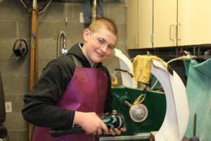 Hilltop Artist Tanner finishes a glass piece in the cold shop