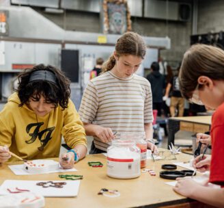 Photo of Hilltop Artists students working on glass fusion pieces in the hot shop