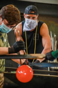 Image of Hilltop Artist Instructor Tony and two Production students working on a piece in the hot shop at Silas HS