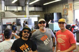 Hilltop Artists instructors Trenton, Greg, and Tony posed in the hot shop during an event