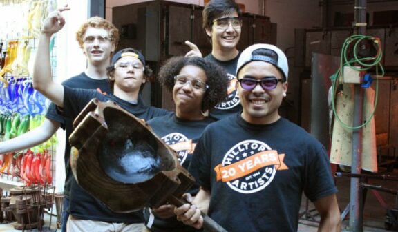 Hilltop Artists Instructor Trenton poses with students in the hot shop