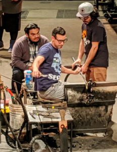 Hilltop Artists David, Tony, and Trenton on the hot shop floor during a demo at the Museum of Glass