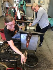Program Director Jessica assist Daytime Teaching Artist Sam on the bench