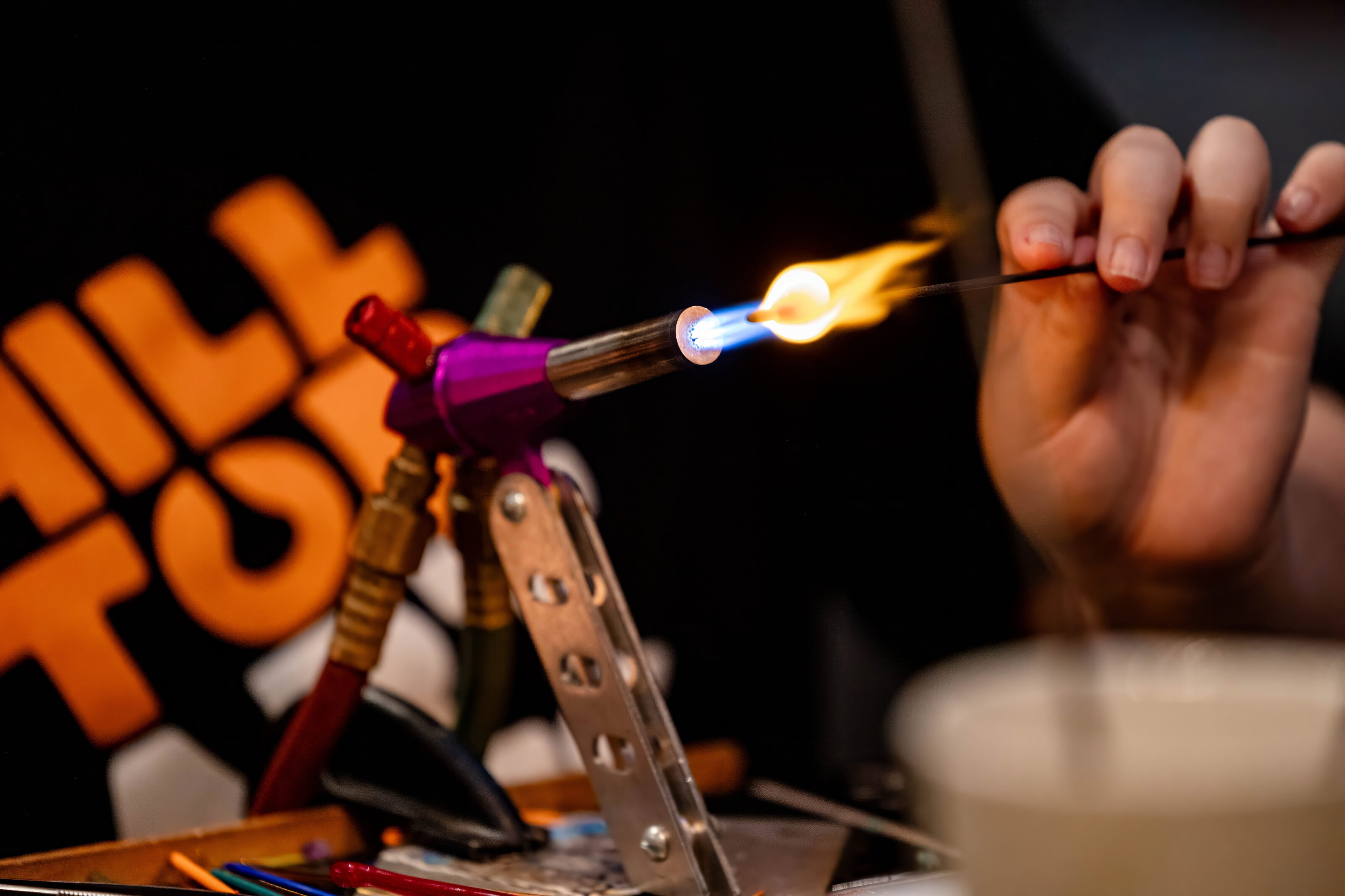 Photograph of a Hilltop Artists student working on a bead torch during a demonstration.