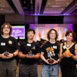 Group photograph of Hilltop Artists students holding glass pumpkins during the 2025 Better Futures Luncheon