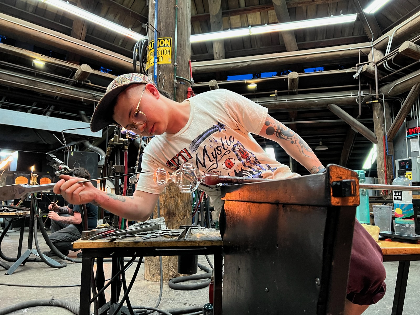 Photograph of artist Alton Bucheimer working on a blown glass piece in the hot shop