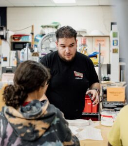 Luis assists a student in the hot shop during the After-School program.