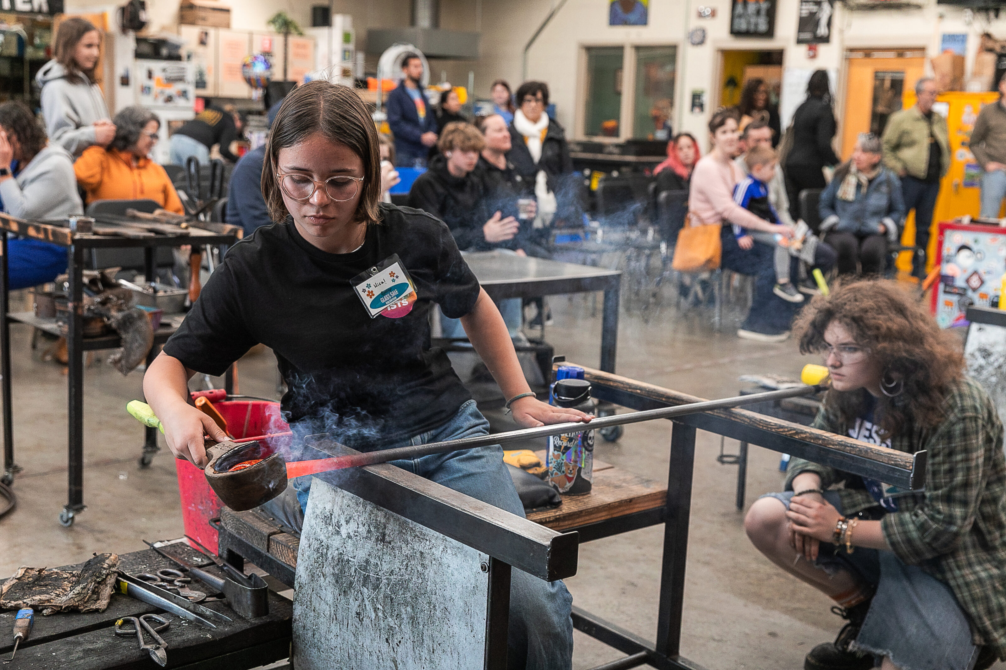 Photograph of two Hilltop Artists students collaborating on a piece during a demonstration at the Spring Glass Sale.