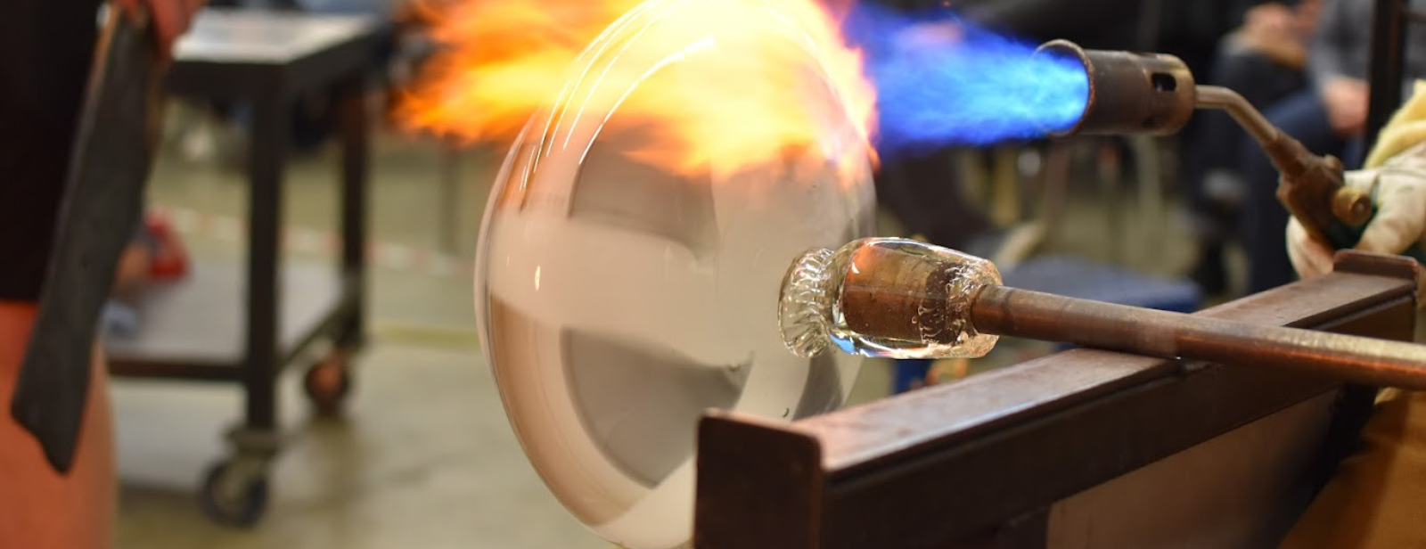 Close up of a blown glass piece on the pipe being heated by a torch