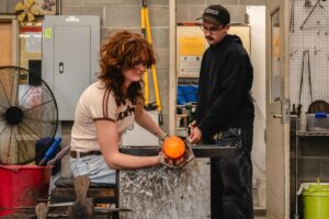 Students collaborate on a piece at the bench in the hot shop at Hilltop Artists