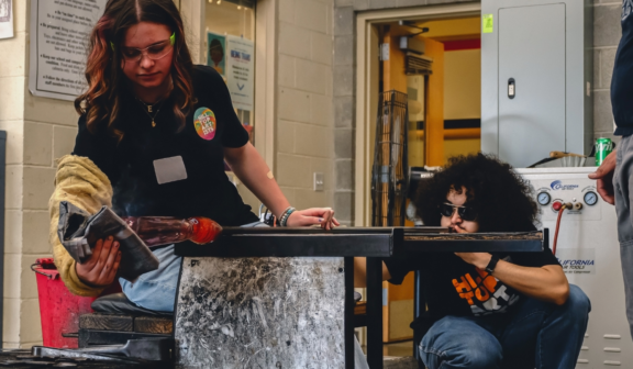 Photo of two Hilltop Artists students collaborating on a piece during a demonstration at the annual Spring Glass Sale